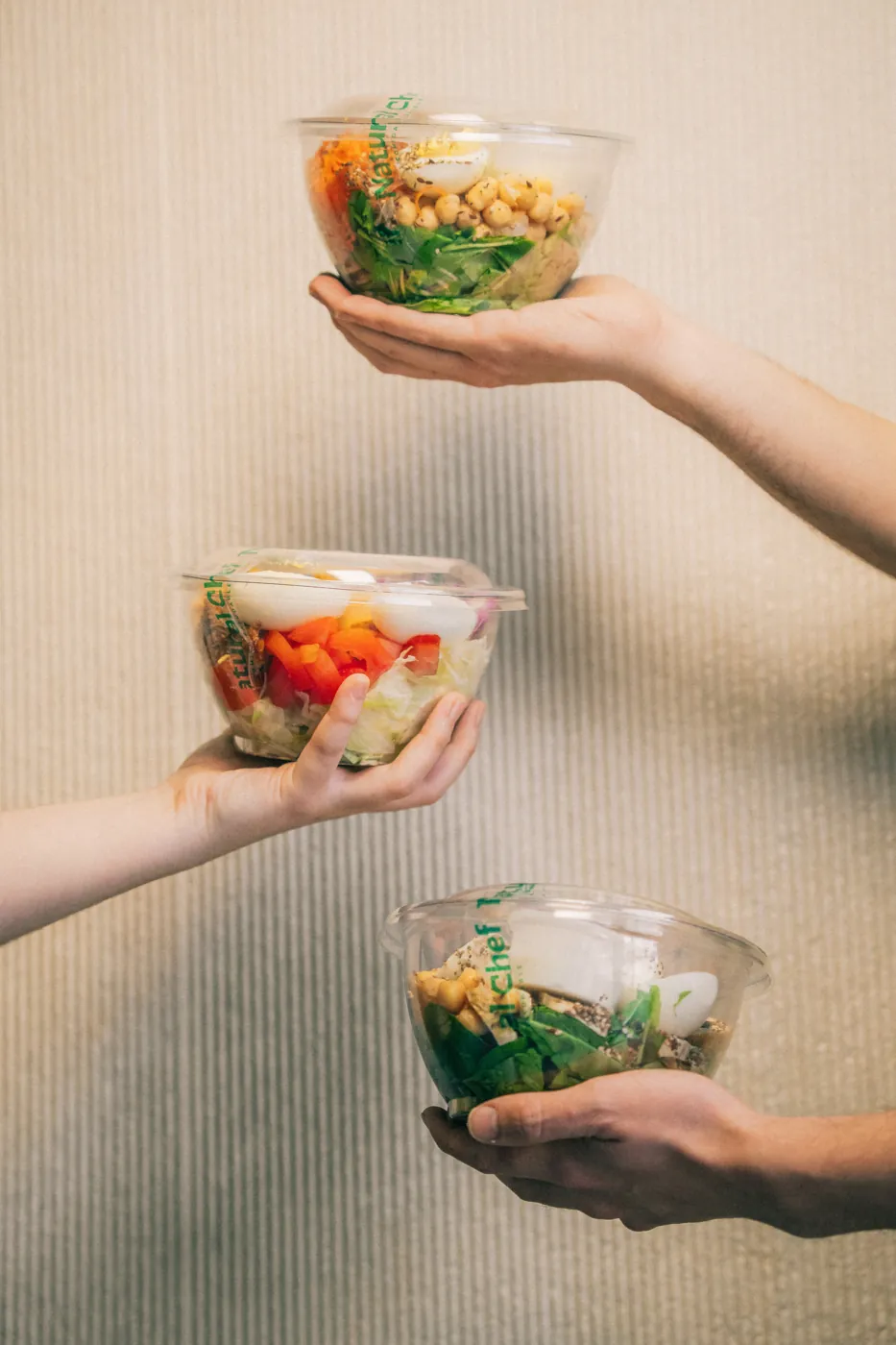 Manos sosteniendo bowls de ensalada