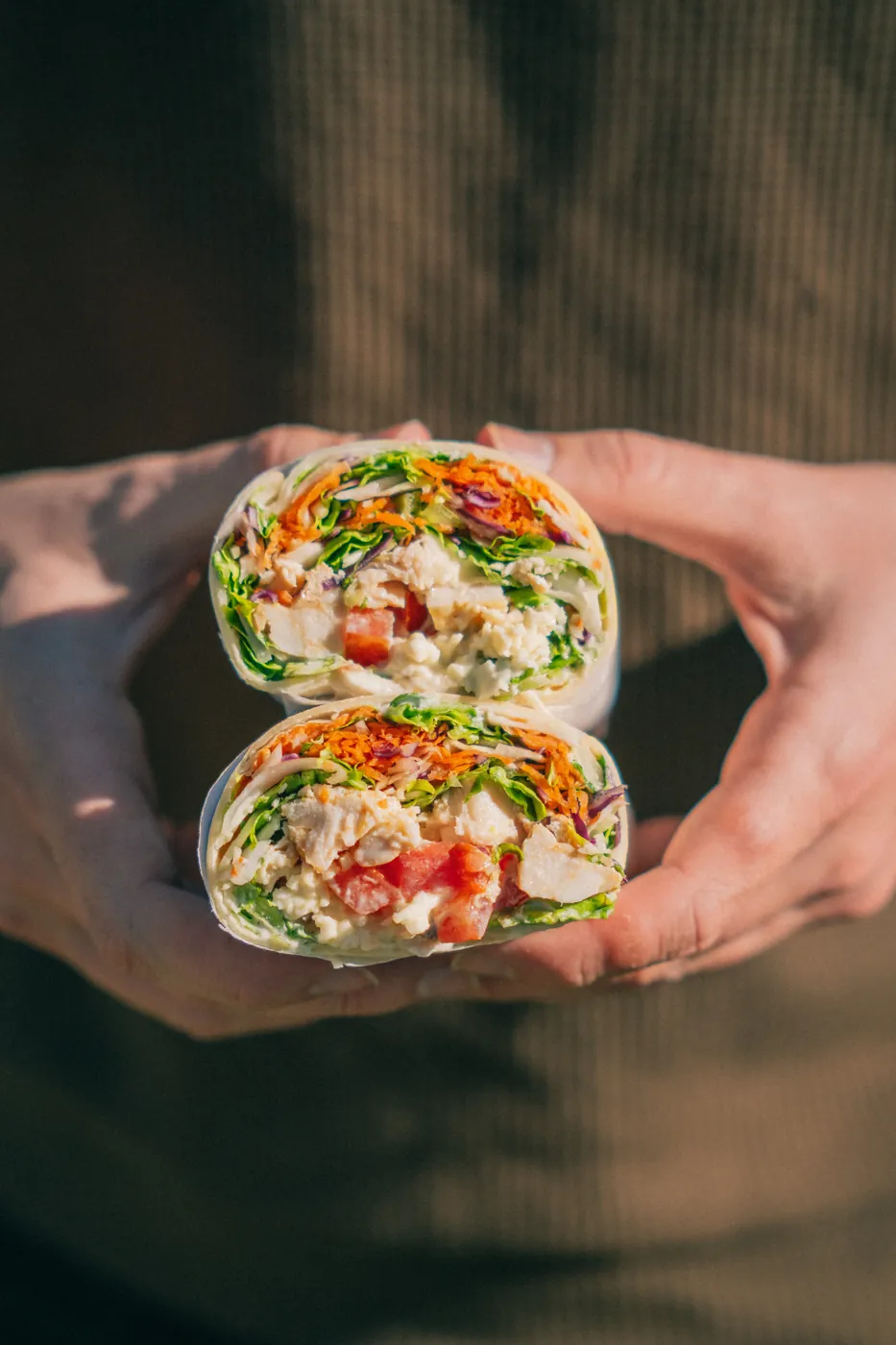 Wrap de pollo sostenido con las dos manos, cortado al medio
